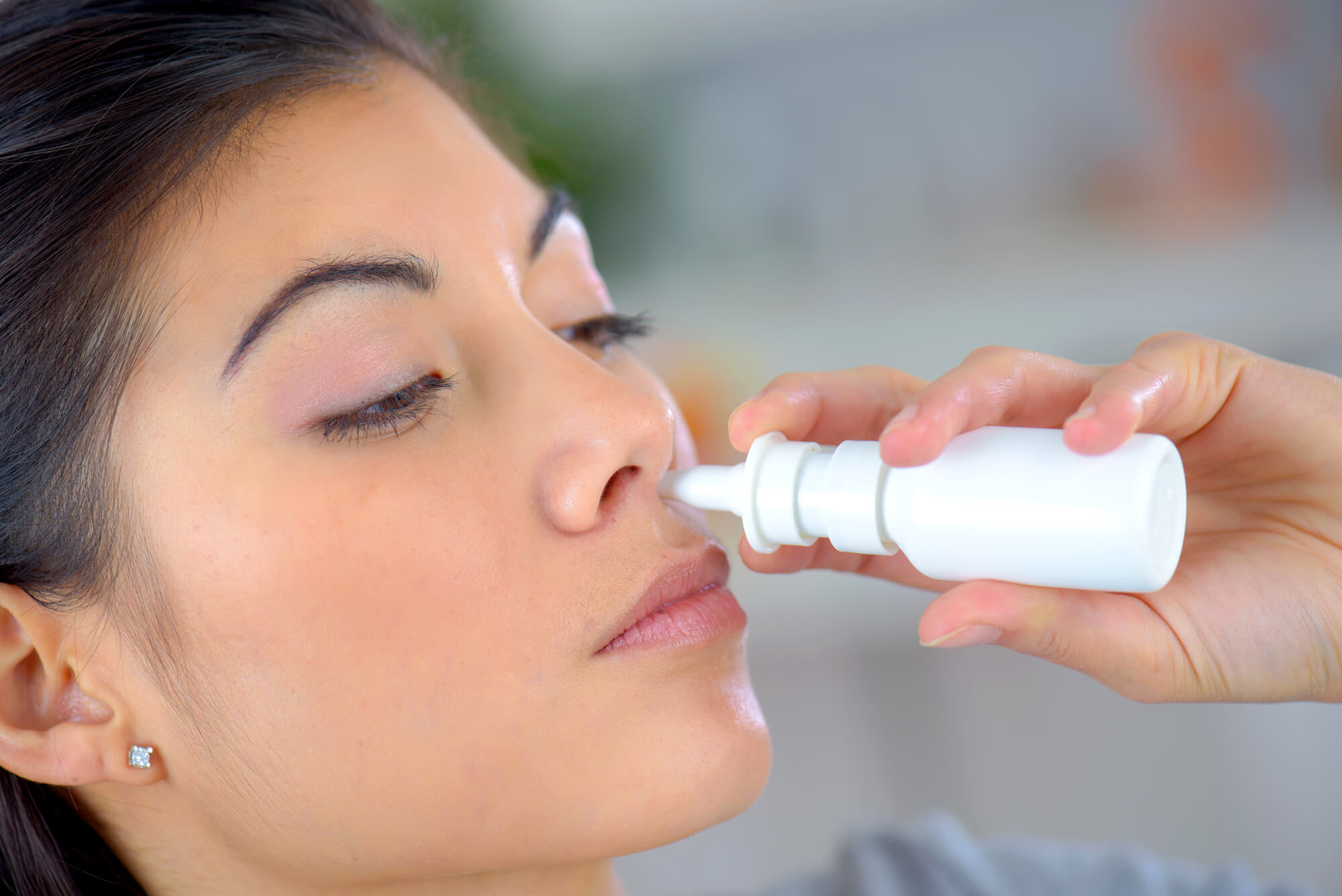 Imagem de mulher asiática fazendo uso de remédio nasal para ilustrar conteúdo sobre hipertrofia de cornetos.